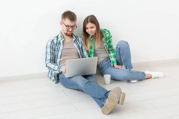 迷人的年轻积极夫妇在休闲服装寻找一个室内设计师为他们的新公寓使用笔记本电脑和高速互联网。公寓设计理念. — 图库照片