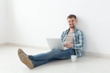 Wi-Fi ve kiralık konut arayışı içinde bir dizüstü bilgisayar kullanarak internette sörf rahat giysi ve gözlük pozitif genç adam. Housewarming ve daire arama konsepti, kopyalama alanı