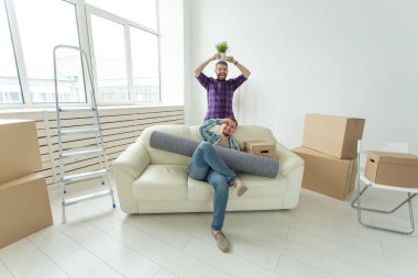 Yeni bir dairenin oturma odasında oturan iki öğrenci erkek arkadaş ellerinde eşyalarını tutarak. Housewarming kavramı