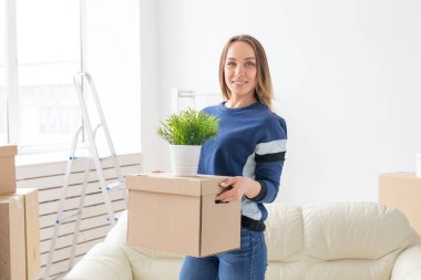 Büyüleyici genç bekar kadın onu gri lop kulaklı İskoç kedi yanında yeni bir dairede ayakta iken hareket ederken şeyler ile bir kutu tutar. Hareketli ve housewarming kavramı.