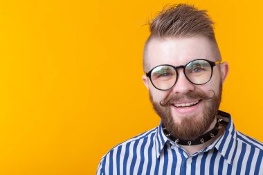 Kopya alanı ile sarı bir arka planda poz gömlek bıyık sakal ve fetiş kolye ile genç pozitif trendy adam hipster. Rock ve alt kültür konsepti.