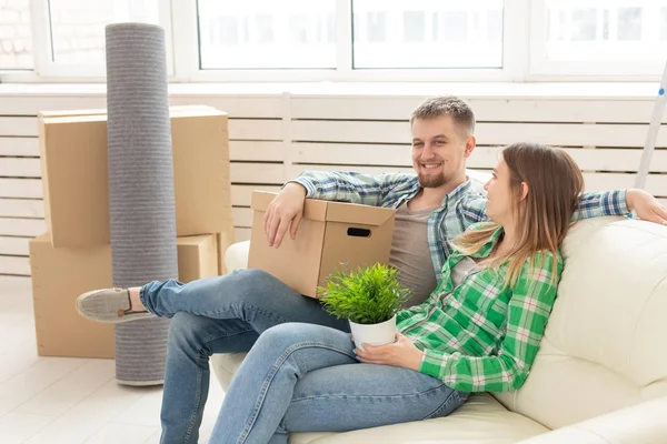 Casal alegre positivo se alegra em mover seu novo apartamento sentado na sala de estar com seus pertences. Conceito de aquecimento doméstico e hipotecas para uma família jovem . — Fotografia de Stock