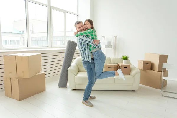 Junges Paar in Jeanshosen, das sich während des Umzugs freudig in ihrer neuen Wohnung umarmt. das Konzept der Wohnungserwärmung und Kredite für neue Wohnungen. — Stockfoto