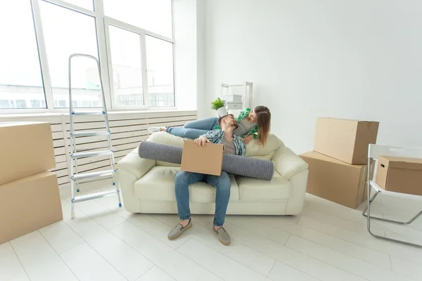 Umzug, Umzug und neues Wohnkonzept - junges Paar vergnügt sich auf der Couch, umgeben von Kisten — Stockfoto