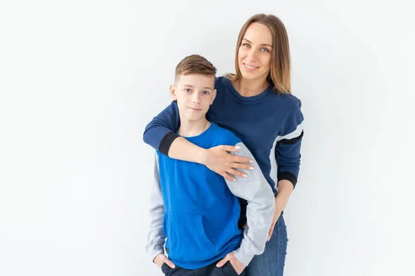 La crianza de los hijos, la familia y el concepto de padre soltero - Una madre feliz y un hijo adolescente riendo y abrazando en el fondo blanco — Foto de Stock