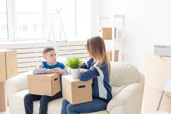 귀여운 싱글 엄마와 어린 소년 아들이 이동 후 물건을 상자를 정렬합니다. 주택 집안일의 개념과 새로운 주택의 기쁨. — 스톡 사진