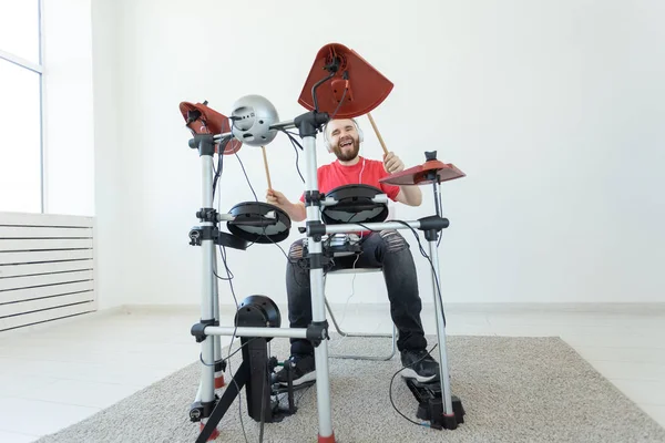 Mensen, muziek en hobby concept-stoere man in rood t-shirt en zwarte sneakers spelen elektronische drum kit — Stockfoto