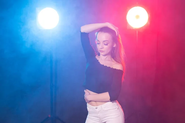 Vida nocturna y concepto de club - mujer joven bailando en la oscuridad bajo las luces —  Fotos de Stock