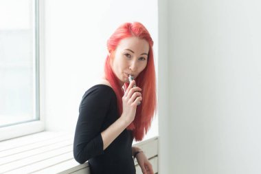 Vape, bağımlılık ve insan kavramı - renkli saçlı genç kadın bir vape sigara