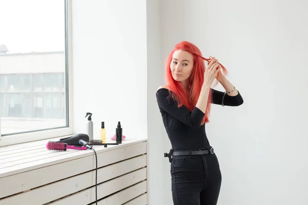 Hermosa chica pelirroja con el pelo largo, ella es teje una trenza, en un salón de belleza. Cuidado profesional del cabello y la creación de peinados . — Foto de Stock