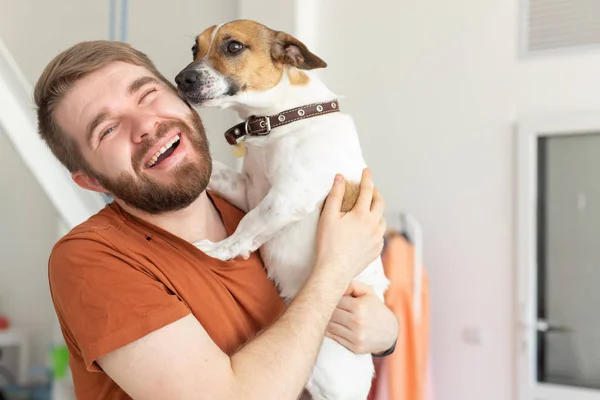 Animal, pet and people concept - Smiling man in casual mustard t-shirt with his jack Russell terrier — стоковое фото