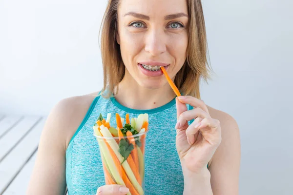 Stile di vita sano donna mangiare verdure sorridente felice in casa. Giovane femmina mangiare cibo sano primo piano . — Foto Stock