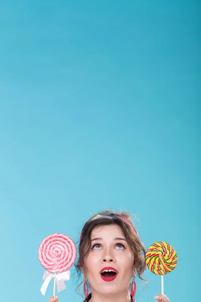 Diet and junk food concept - pin-up woman looking up on blue background with copy space