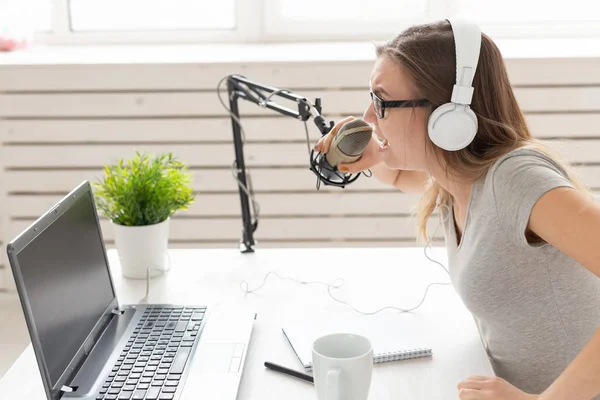 Concepto de presentador de radio - Mujer trabajando como presentadora de radio sentada frente al micrófono sobre fondo blanco en el estudio — Foto de Stock