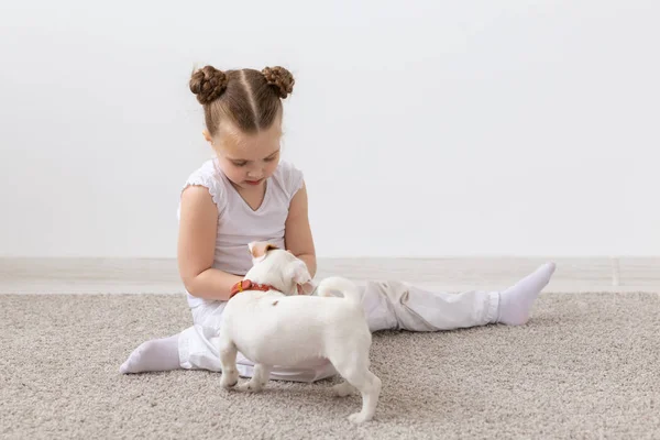 Niños, mascotas y concepto animal - Niña jugando con su cachorro Jack Russell Terrier en interiores — Foto de Stock