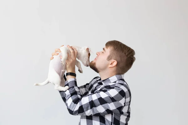 Concepto de personas, mascotas y animales - hombre joven besando gato russell terrier cachorro sobre fondo blanco — Foto de Stock