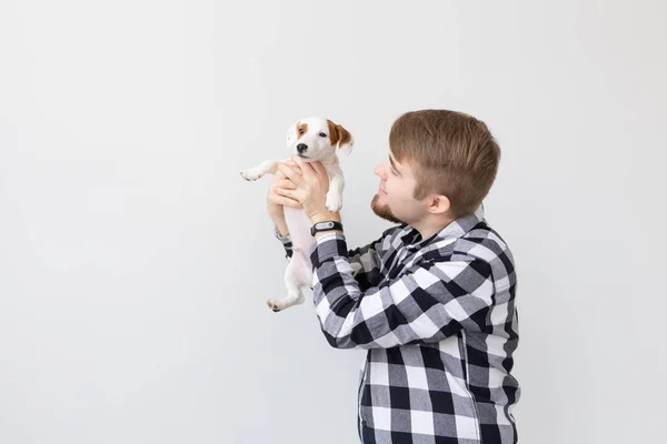 Conceito de pessoas, animais de estimação e animais - jovem segurando Jack Russell terrier filhote de cachorro no fundo branco — Fotografia de Stock