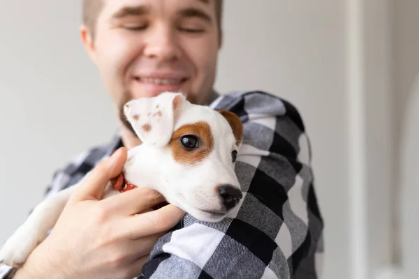 Concepto de personas, mascotas y animales - primer plano de hombre joven abrazando gato russell terrier cachorro sobre fondo blanco — Foto de Stock