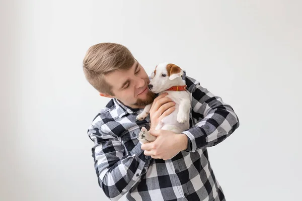 Concepto de personas, mascotas y animales - hombre guapo sosteniendo gato russell terrier cachorro sobre fondo blanco — Foto de Stock