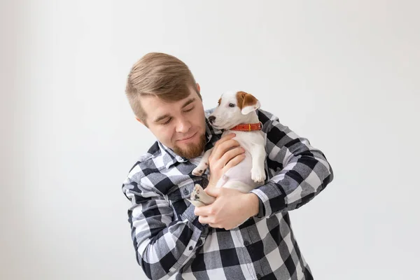 Concepto de personas, mascotas y animales - primer plano de hombre joven sosteniendo gato russell terrier cachorro sobre fondo blanco — Foto de Stock