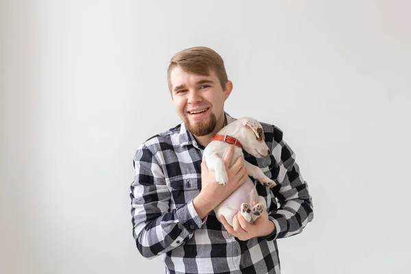 Concepto de personas, mascotas y animales - primer plano de hombre joven sosteniendo gato russell terrier cachorro sobre fondo blanco — Foto de Stock