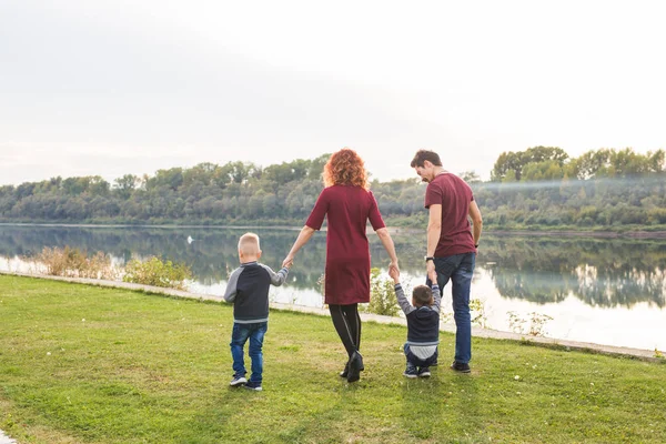 Elternschaft und Naturkonzept -Familie aus Mutter und Vater mit zwei Jungen Zwillingskinder in einem Park im Sommer an einem Fluss bei sonnigem Tag — Stockfoto