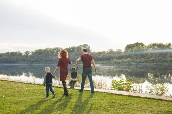 Eltern, Kindheit und Naturkonzept - Familie spielt mit zwei Söhnen am Wasser — Stockfoto