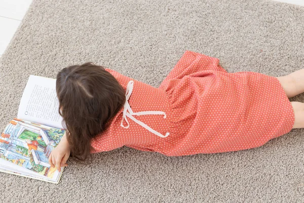 Mädchen liegt auf dem Boden und liest ein Buch. — Stockfoto