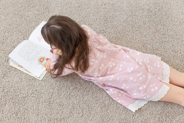 Mädchen liegt auf dem Boden und liest ein Buch. — Stockfoto