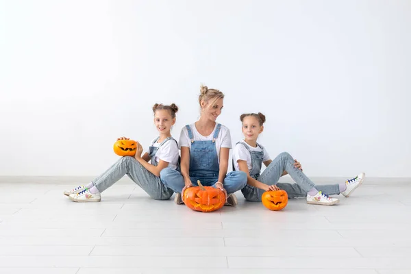 Buon Halloween e le vacanze concetto - Una madre e le sue figlie con le zucche. Famiglia felice che si prepara per Halloween . — Foto Stock