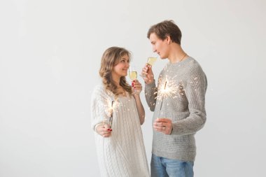 Yeni yıl, tatiller, tarih ve sevgililer günü konsepti - Beyaz arka plan üzerinde kıvılcımLar ışık ve şampanya bardak tutan Loving çift