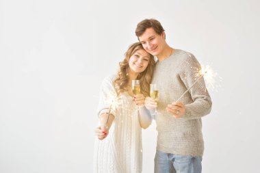 Yeni yıl, tatiller, tarih ve sevgililer günü konsepti - Beyaz arka plan üzerinde kıvılcımLar ışık ve şampanya bardak tutan Loving çift