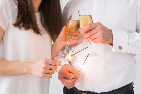 Nieuwjaar, vakantie, datum en Valentines Day concept-liefdevolle paar Holding wonderkaarsen licht en glazen champagne close-up over witte achtergrond — Stockfoto