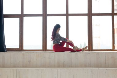 Hayal kurma, düşüncelilik ve yalnızlık konsepti - Genç beyaz kadın oturma odasında oturuyor ve büyük pencereden dışarı bakıyor