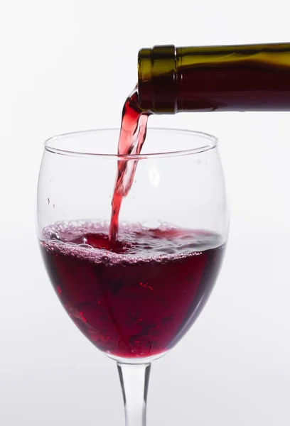 Pouring red wine into the glass on white background, close-up Royalty Free Stock Photos