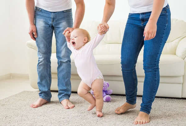 Concepto de familia, hijos y paternidad - Padres enseñando a caminar a la niña —  Fotos de Stock