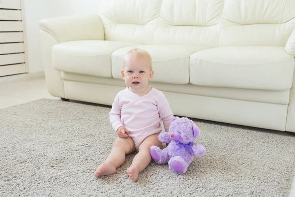 Linda niña pequeña con ropa rosa sentada en la alfombra — Foto de Stock