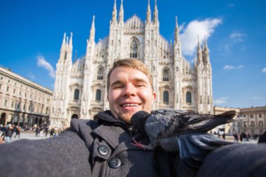 Kış seyahat, tatil ve kuşlar kavramı - selfie güvercinler yakınındaki Milan Katedrali Duomo di Milano, İtalya ile alarak genç komik adam.