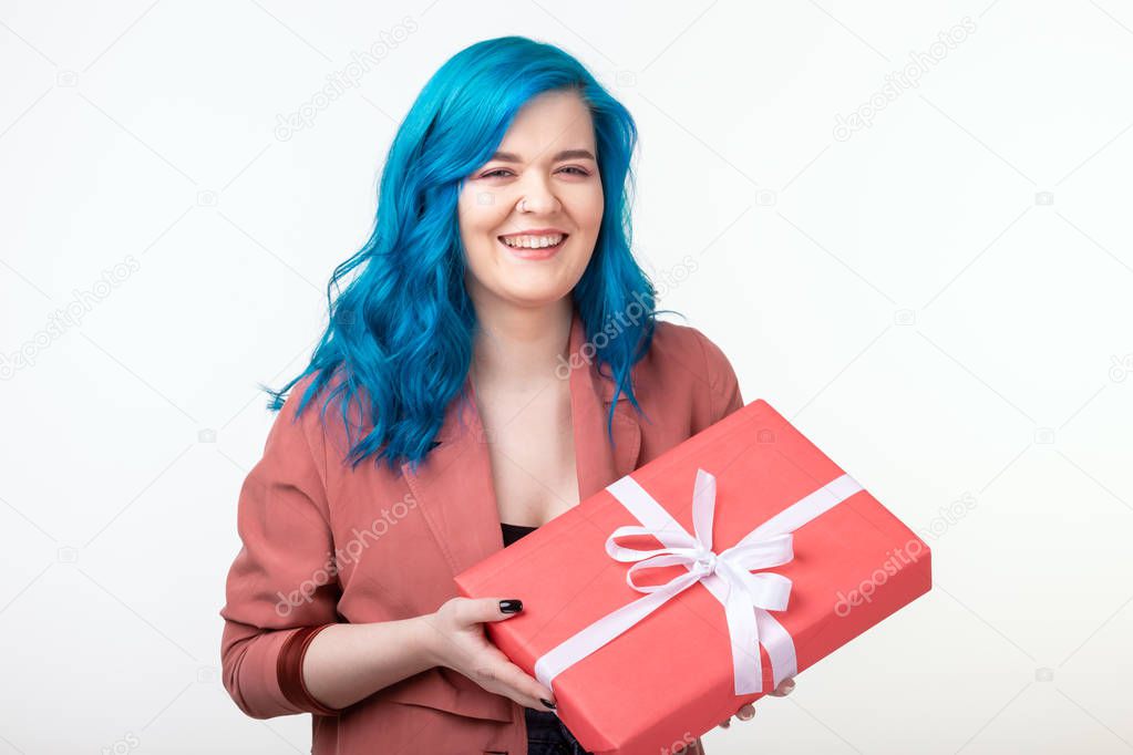 People, holidays and fashion concept - Surprising woman with blue hair holding a gift box on white background