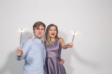 Parti, kutlama, olay ve tatil kavramı - giyinmiş adam mavi gömlek ve mor elbise ambarda giymiş kadın havai fişek sopa