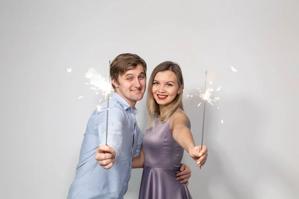 Festa, celebração, evento e feriados conceito homem vestido de camisa azul e mulher vestida de vestido roxo segurar um pau de fogo de artifício — Fotografia de Stock