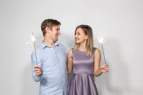 お祝い、パーティー、休日コンセプト - 幸せな男と花火と灰色の背景の上を抱いて女 — ストック写真