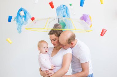 Çevre kirliliği, plastik geri dönüşüm sorunu ve ekoloji sorunu kavramı - beyaz arka plan üzerinde çöp altında üzgün aile.