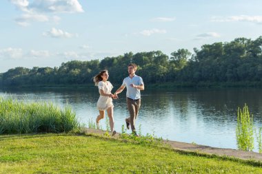 Aşk ve ilişki kavramı - mutlu erkek ve kadın bir göl yakınındaki bir parkta çalışan