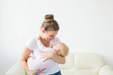 Genç mutlu sevgi dolu anne pencereye karşı kollarında onun bebek kızı tutarak. Anne bakımı. Çocuk bakımı.