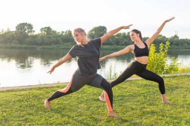 Küçük kadın fitness grubu güneşli bir günde parkta yoga yapıyor