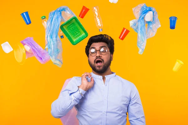 Problema de la basura, el reciclaje de plástico, la contaminación y el concepto ambiental - sorprendido hombre que lleva la bolsa de basura en el fondo amarillo — Foto de Stock