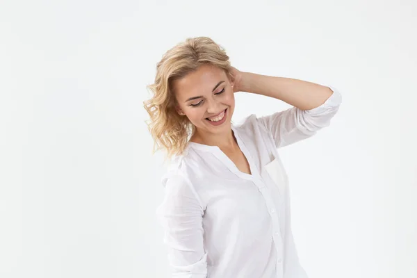 Souriant charmante jeune femme blonde debout sur un fond blanc. Concept de jeune fille insouciante — Photo