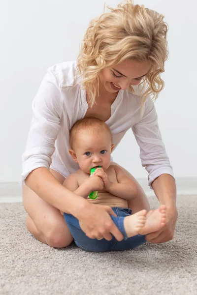 Conceito de família e parentalidade - Bebê bonito brincando com sua mãe no tapete bege — Fotografia de Stock