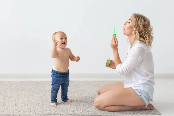 Conceito de família e parentalidade - Bebê bonito brincando com sua mãe no tapete bege — Fotografia de Stock